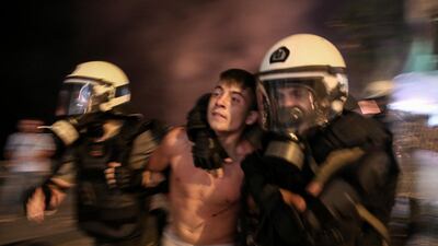 A young protester is detained by riot policemen during clashes outside an international trade fair in Greece. AP