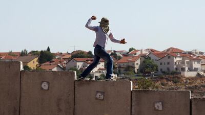 A file photo of a Palestinian youth stands on top of Israel's separation barrier as he throws stones at Israeli forces (unseen) during a weekly protest in the West Bank village of Nilin. Israeli prime minister Benjamin Netanyahu has suggested hardening the rules towards Palestinian stone-throwers. Abbas Momani/AFP Photo