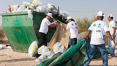 Volunteers help clear away rubbish at a campsite in Nad Al Sheba.