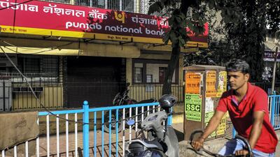 A cyclist rides past a Punjab National Bank branch in Mumbai. The bank is among the lenders lined up for mergers in India. Bloomberg