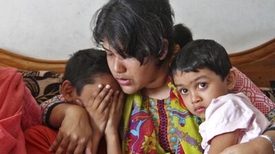 A relative consoles son Mahir Akter (L) and daughter Tabbsum (R) of Mahmuda Mitu, wife of a antiterror police officer who was killed stabbed and shot in Chittagong by suspected extremists. EPA