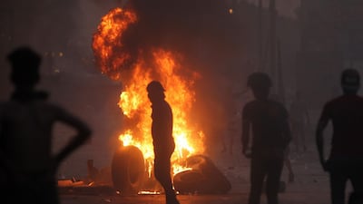 Iraqi demonstrators stand behind a tyre fire during a demonstration in Baghdad. AFP