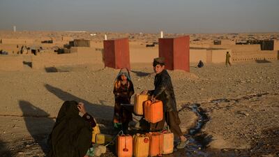 A woman and children fill tanks with water at a displaced persons camp in Herat province, Afghanistan. AFP