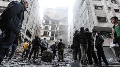 Palestinians gather in front of damaged buildings in Gaza City following Israeli air strikes. AFP Photo