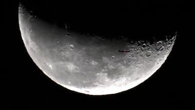 A passenger plane with the waning crescent Moon as it rises over Kuwait City. AFP