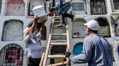 A relative of a victim of the Colombian armed conflict hands the urn with the remains of his loved ones to a gravedigger at the cemetery in Dabeiba, Antioquia department, Colombia. AFP