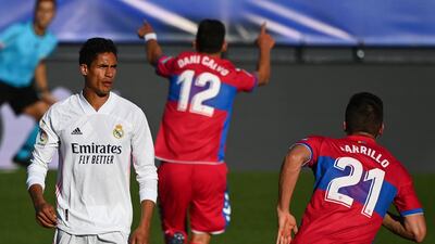 Real Madrid's French defender Raphael Varane reacts as Elche's players celebrate their goal. AFP