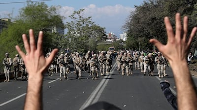 A demonstrator holds up his hands toward advancing soldiers during a protest as a state of emergency remains in effect in Santiago, Chile, Sunday, October 20, 2019. AP