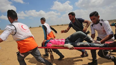 Palestinians carry a protester injured during clashes with Israeli forces along the border with the Gaza strip east of Khan Yunis, as Palestinians protest over the inauguration of the US embassy following its controversial move to Jerusalem. Said Khatib / AFP