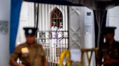 Devotees look out from a mosque as security personnel stand guard during Friday noon prayer in Colombo. AFP