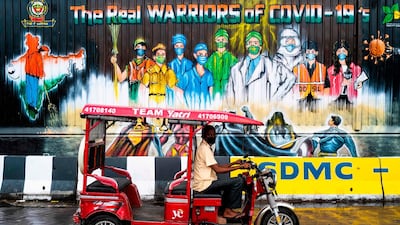 An electic-rickshaw drier rides past a mural painted on a garbage dump after the government eased a nationwide lockdown imposed as a preventive measure against the coronavirus in New Delhi. AFP