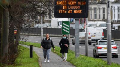People walk past a roadside public health information sign in London. Reuters