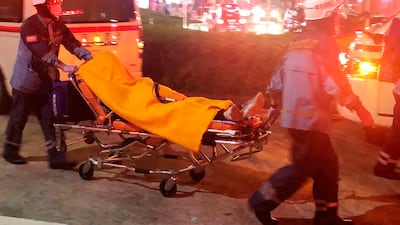Rescuers carry an injured passenger on stretcher at Soshigaya Okura Station after stabbing on a commuter train, in Tokyo Friday night, Aug. 6, 2021. A man with a knife attacked 10 passengers on a commuter train in Tokyo on Friday and was arrested by police after fleeing, fire department officials and news reports said. (Kyodo News via AP)
