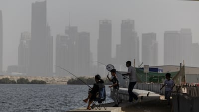 A family fishes off the breakwater along the Creek extension behind Business Bay on a hazy day in Dubai. Antonie Robertson/The National
