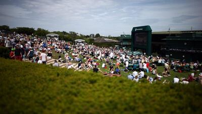 Spectators relax in the sun on Murray Mound as a large television screen shows the match on centre court on Day1 of the 2015 Wimbledon championship on Monday. Carl Court / Getty Images