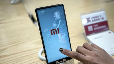 A customer looks at a Xiaomi smartphone in a shop in Beijing on May 3, 2018. - Chinese smartphone maker Xiaomi has kicked off what is expected to be the world's biggest initial public offering (IPO) of shares in years after it filed documents with Hong Kong's stock exchange. (Photo by FRED DUFOUR / AFP)