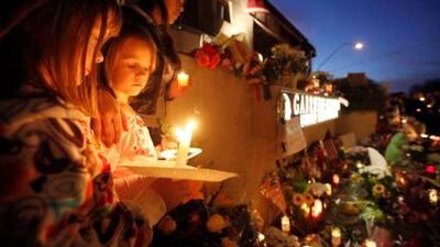 Ellie Steve, 6, Lucia Reeves, 6, and Zoe Reeves, 18, gather for a candlelit vigil outside the offices of Gabrielle Giffords in Tucson, Arizona,. Ms Giffords was critically wounded during a shooting at a political event in Tucson.