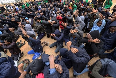 Migrants raise their hands, crossed in a gesture protesting against their detention at a shelter in Libya. AFP