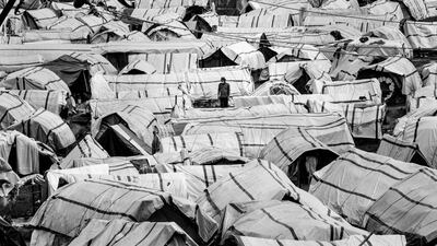 A man walks between hundreds of tents in a camp for displaced people on the outskirts of Kathmandu, Nepal, in 2015. Months after Nepal was hit by the earthquake, hundreds of thousands of people were still living in temporary shelters waiting for their homes to be rebuilt. Photo: Omar Havana/ Xposure Photo Festival