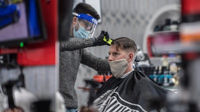 A hairdresser, wearing gloves, a protective face mask and a face shield, cuts the hair of a client in Vienna. EPA