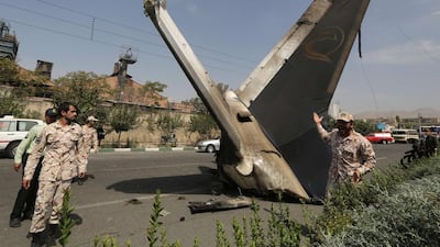 A member of the Iranian Revolutionary Guards stands next to the remains of a plane that crashed near Tehran's Mehrabad airport. A civilian airliner crashed on take-off near the Mehrabad airport in the capital, Iranian news agencies said, with reports that almost 50 people were killed. Atta Kenare / AFP