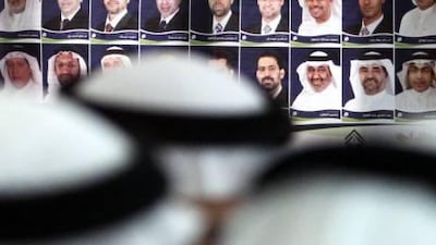 Members of Bahrain’s opposition Al Wefaq National Islamic Society gather yesterday in Manama in front of a poster of its candidates who ran in Saturday’s parliamentary elections.