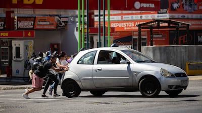 People push a car past a petrol station in Caracas, Venezuela. The country has the largest oil reserves in the world. EPA