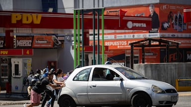 People push a car past a petrol station in Caracas, Venezuela. The country has the largest oil reserves in the world. EPA