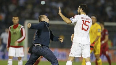 A Serbian fan prepares to punch Albania's Mergim Mavraj as fans invaded the pitch in the chaos following Tuesday's flag incident during the Euro 2016 qualifier between Serbia and Albania in Belgrade. Marko Djurica / Reuters