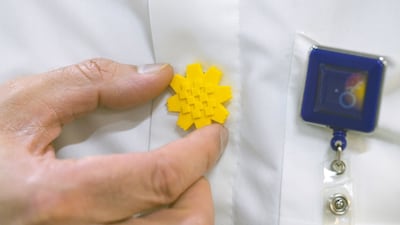 A Kuwaiti man attaches an arfaj flower pin on his shirt in Kuwait City on April 7, 2026. The flower symbolises strength and perseverance. AFP