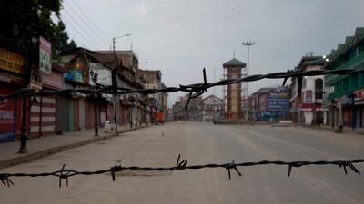 A deserted street is seen through barbwire set up as a blockade during curfew in Srinagar, Indian controlled Kashmir. AP