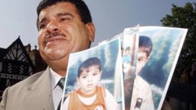 Daoud Mousa holds pictures of his grandchildren outside the High Court in London, where he is alleging that his son Baha died in the custody of British soldiers in southern Iraq last year.