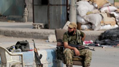A Turkey-backed Syrian rebel fighter sits on a chair along a street in the border town of Tal Abyad, Syria, October 16, 2019. REUTERS/Khalil Ashawi