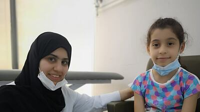 Dr Fatimah Al Marzouqi sits with Karma Elsawir, 7, at Al Madina clinic in Ajman before the girl was immunised against Covid-19. All photos: Salam Al Amir / The National