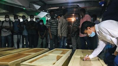 A man writes on the coffin of a burns victim after the gas explosion at a mosque on September 6, 2020. AP