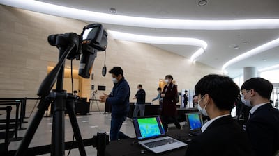 Attendees wearing protective masks walk through a temperature screening point as they arrive at the Samsung Electronics Co in South Korea. Bloomberg