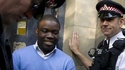 Kweku Adoboli, center, smiles as he head towards a security van in London. AP Photo