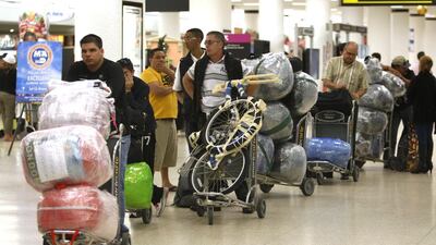 File photo of travellers waiting in line with their luggage at Miami International Airport before traveling Cuba in Miami. On September 1, 2014, the Cuban government will enact new rules meant to take a big bite of that traffic, sharply limiting the amount of goods people can bring into Cuba in their luggage, and ship by boat from abroad. Lynne Sladky/AP Photo