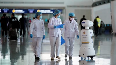 Medical workers walk by a police robot at the Wuhan Tianhe International Airport. Reuters