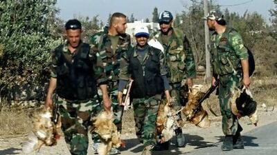 Syrian army soldiers carry chickens in the village of Buweida, north of Qusayr, in central Homs province on Friday. AFP