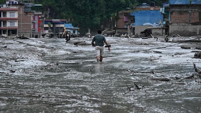 A resident walks along a street covered in mud following flash floods and a landslide disaster in Devghat, in Nepal's Nuwakot district. Photo: AFP