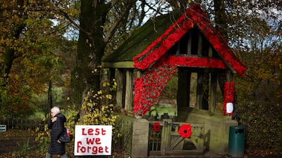 A woman walks past an installation made out of knitted poppies at the entrance to Christ Church in Burbage. Reuters