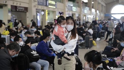 A woman carries a child as she walks past waiting travelers inside the Hankou railway station in Wuhan, Hubei Province, China. Bloomberg
