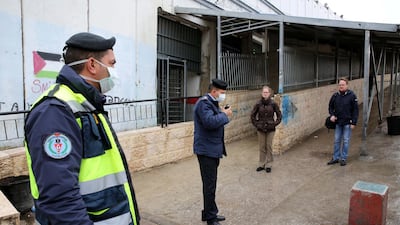 Palestinian security forces wearing masks block the entrance to the crossing gate between the Israeli occupied West Bank city of Bethlehem and Jerusalem that remained closed on March 6, 2020. EPA