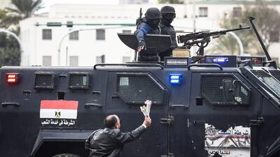 An Egyptian man offers flowers to police special forces patrolling on Cairo's landmark Tahrir Square on January 25, 2016, as the country marks the fifth anniversary of the 2011 uprising that toppled Hosni Mubarak amid tight security. Mohamed El Shahed/AFP