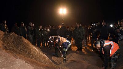 In this photo released on December 30, 2017, by the Syrian official news agency, Sana, Syrian security forces work at the site of two mass graves believed to contain the bodies of civilians and troops killed by ISIS, in the village of Wawi near the northern city of Raqqa, Syria. AP