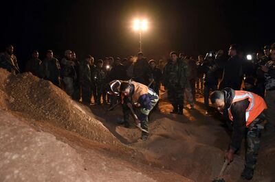 Syrian security forces work at the site of two mass graves believed to contain the bodies of civilians and troops killed by ISIS in the village of Wawi near the northern city of Raqqa. AP