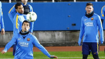 Barcelona’s Luis Suarez watches the ball as Dani Alves and Lionel Messi watch him on Monday during training. Shizuo Kambayashi / AP