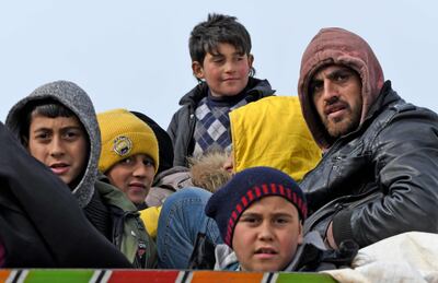Displaced Syrians ride in the back of a truck near the Turkish border in the rebel-held part of Syria's Aleppo province on February 14, 2020. AFP