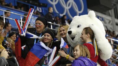 Ice hockey fans pose for a photograph with an Olympic bear mascot during the women’s preliminary hockey game between USA and Finland. Jim Young/Reuters